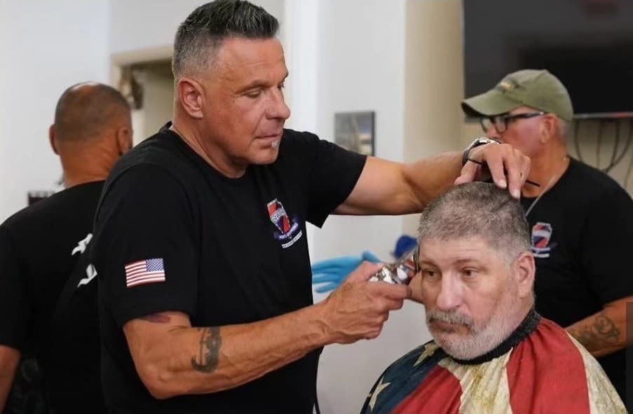 A volunteer barber giving a haircut to a veteran at a PrayerCuts! event